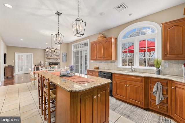 kitchen with pendant lighting, dishwasher, a stone fireplace, sink, and a kitchen island