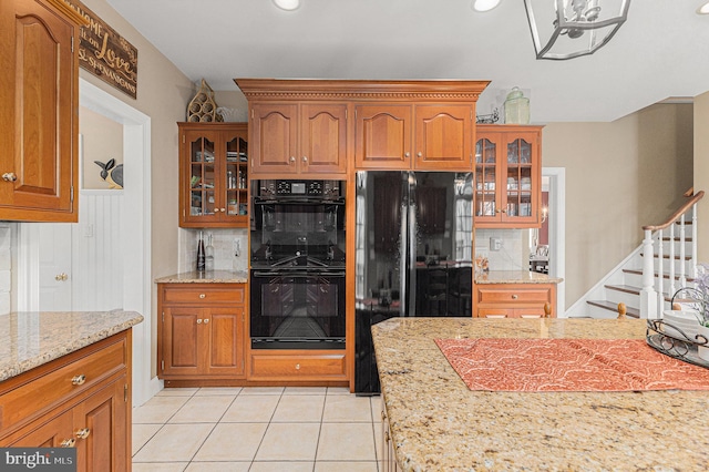 kitchen with black appliances, decorative backsplash, light tile patterned flooring, and light stone counters