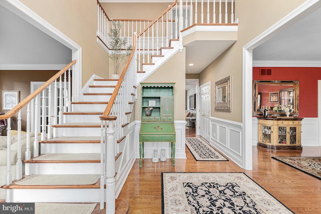 stairs with hardwood / wood-style flooring, ornamental molding, and a high ceiling