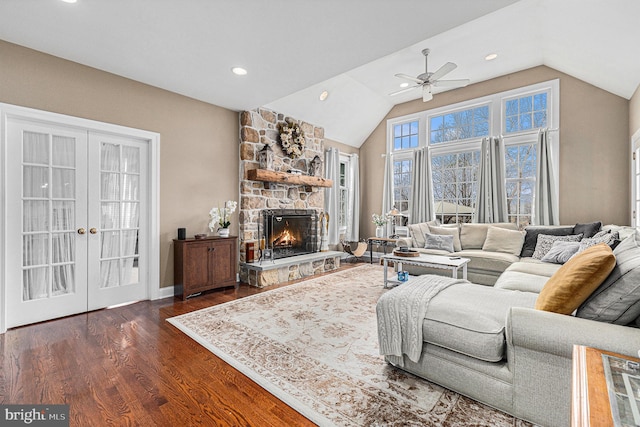 living room with ceiling fan, french doors, dark wood-type flooring, a stone fireplace, and vaulted ceiling