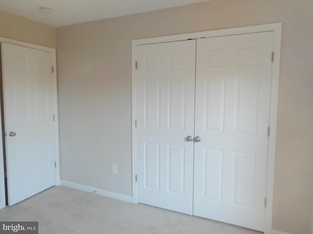 unfurnished bedroom featuring light colored carpet and a closet