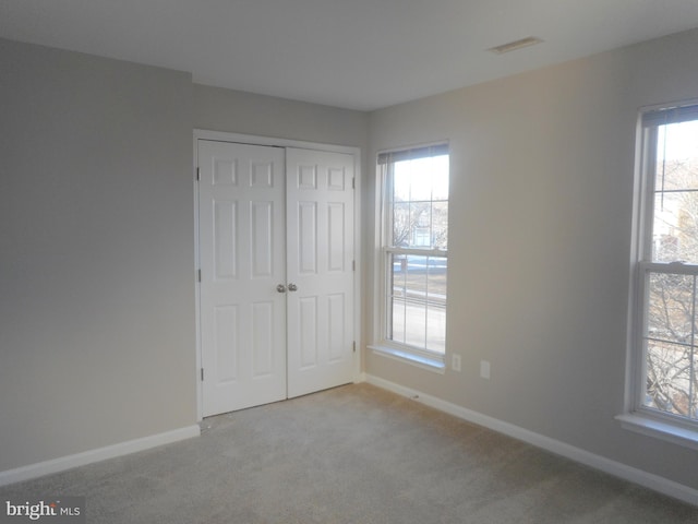 unfurnished bedroom featuring light colored carpet and a closet