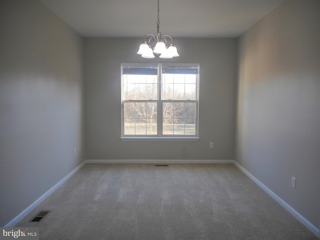 carpeted spare room featuring a chandelier