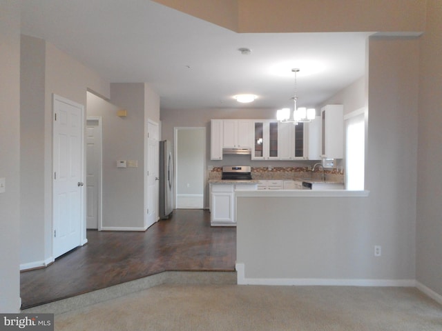 kitchen featuring appliances with stainless steel finishes, pendant lighting, white cabinetry, sink, and an inviting chandelier