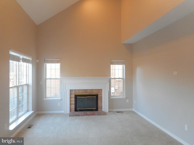 unfurnished living room featuring a brick fireplace, light colored carpet, and high vaulted ceiling