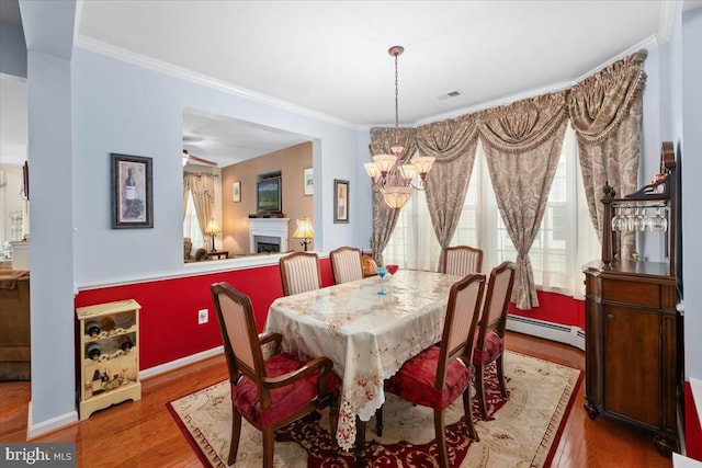 dining area with a chandelier, crown molding, hardwood / wood-style floors, and a baseboard radiator