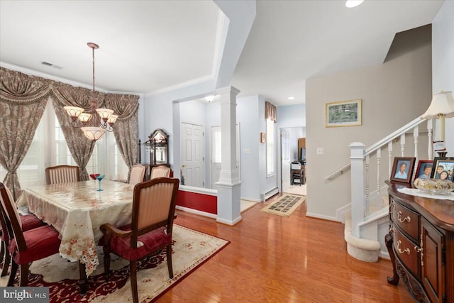 dining room featuring decorative columns, ornamental molding, a baseboard radiator, light hardwood / wood-style flooring, and a chandelier