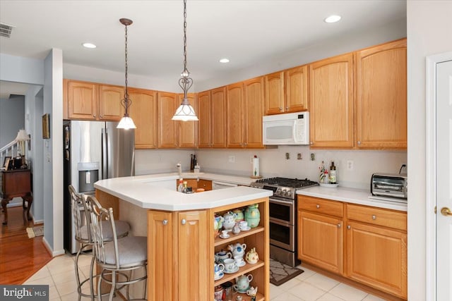 kitchen featuring pendant lighting, a breakfast bar, light tile patterned floors, an island with sink, and stainless steel appliances