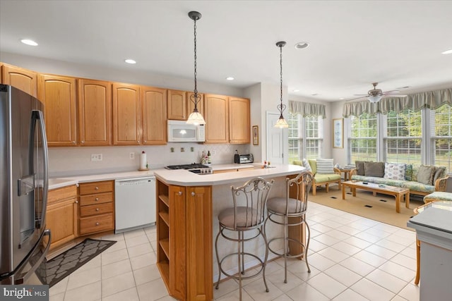 kitchen with pendant lighting, ceiling fan, light tile patterned floors, appliances with stainless steel finishes, and a kitchen island