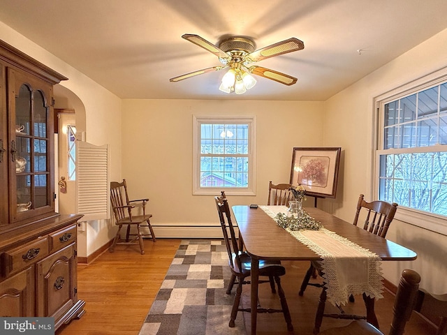 dining area with wood-type flooring, baseboard heating, and ceiling fan