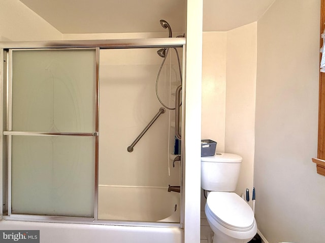 bathroom with toilet and shower / bath combination with glass door