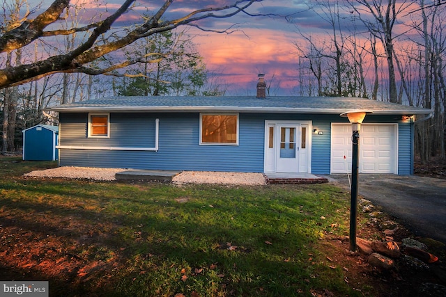 ranch-style home with a yard, a garage, and a storage unit