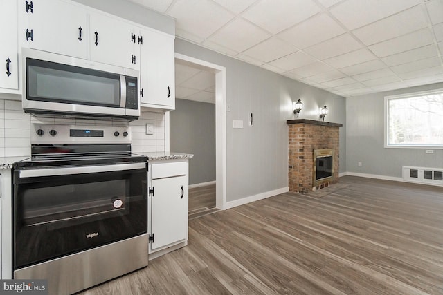 kitchen featuring light wood-type flooring, backsplash, stainless steel appliances, and white cabinetry