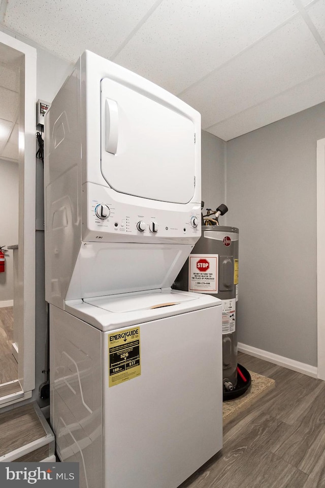 laundry area featuring dark hardwood / wood-style flooring, stacked washing maching and dryer, and water heater