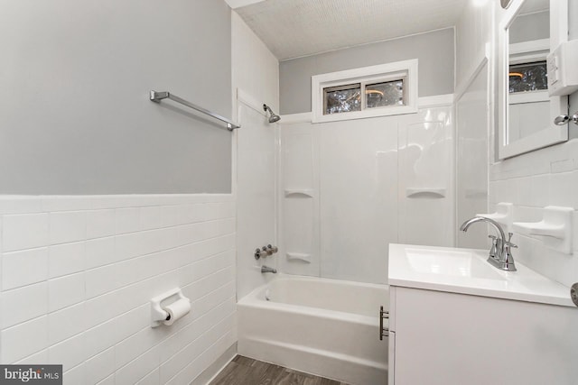 bathroom with hardwood / wood-style floors, a textured ceiling, shower / bathtub combination, and tile walls