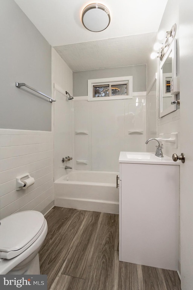 full bathroom featuring vanity, shower / washtub combination, wood-type flooring, tile walls, and toilet