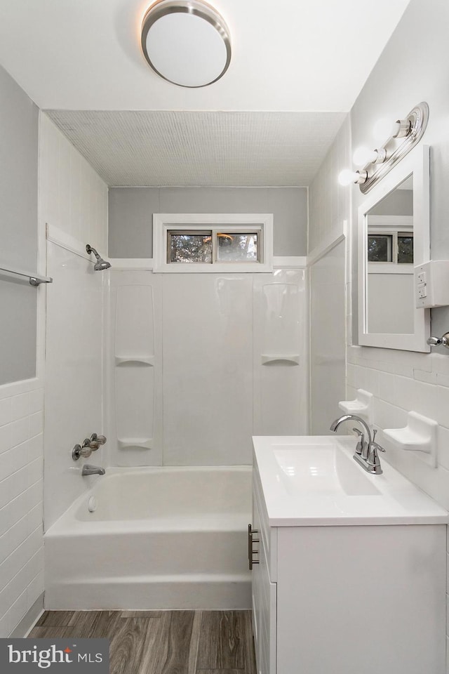 bathroom featuring hardwood / wood-style floors, vanity, shower / washtub combination, and tile walls