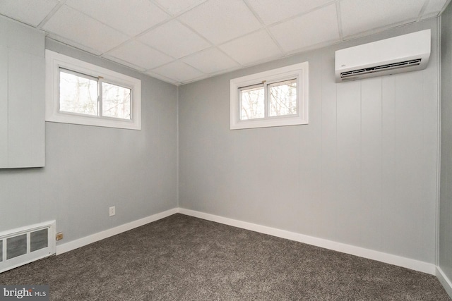 basement with carpet flooring, a drop ceiling, and a wall unit AC