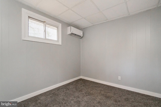 basement featuring an AC wall unit, a paneled ceiling, and carpet