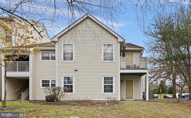 rear view of house with a yard and a balcony