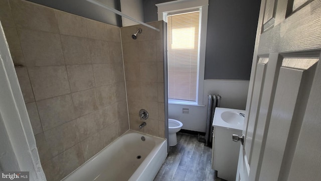 full bathroom featuring hardwood / wood-style flooring, vanity, toilet, and tiled shower / bath combo