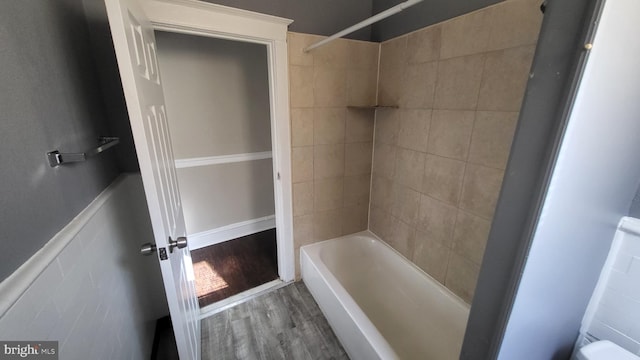 bathroom with hardwood / wood-style floors and tiled shower / bath