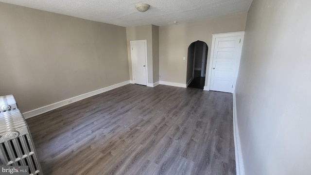 spare room featuring dark wood-type flooring and a textured ceiling