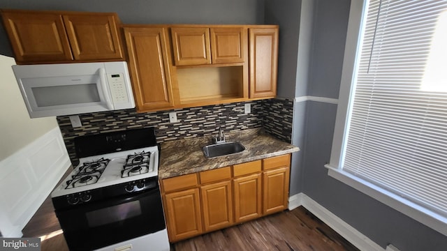 kitchen with decorative backsplash, white appliances, sink, dark stone countertops, and dark hardwood / wood-style floors