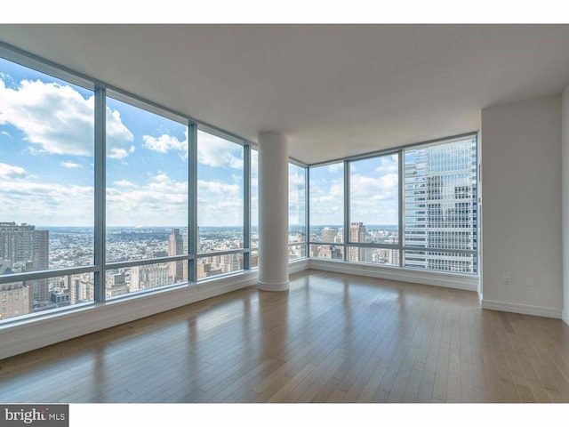 1414 S Penn Sq S Unit 45Gh, Philadelphia, PA 19102 - empty room featuring a view of city, plenty of natural light, wood finished floors, and baseboards