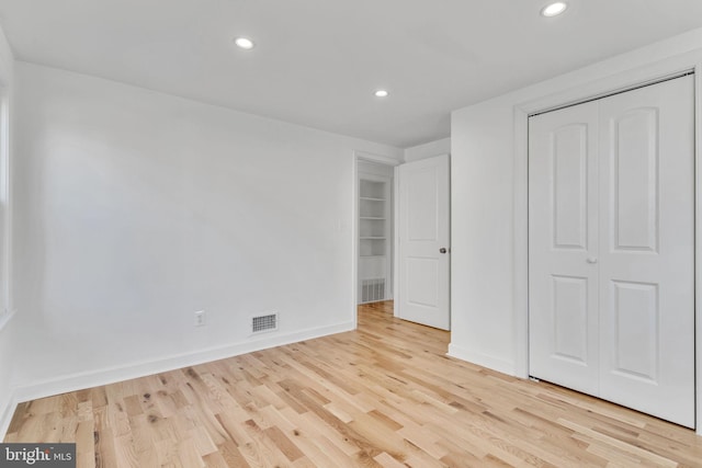 unfurnished bedroom with light wood-type flooring and a closet