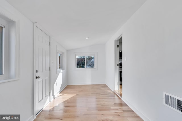 hallway featuring vaulted ceiling and light hardwood / wood-style flooring