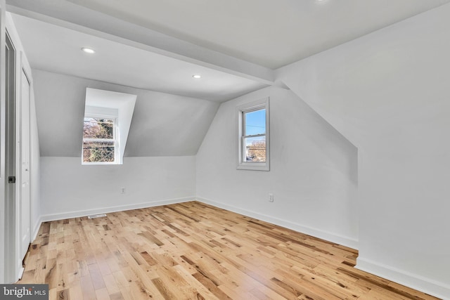 bonus room featuring light hardwood / wood-style floors, vaulted ceiling, and a healthy amount of sunlight