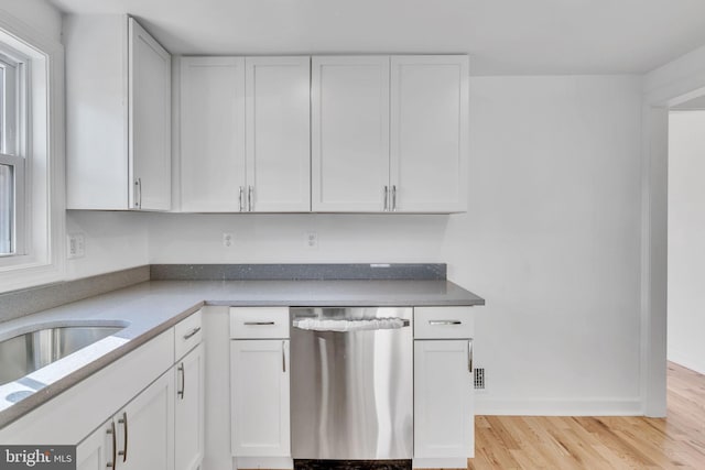 kitchen with a healthy amount of sunlight, white cabinetry, stainless steel dishwasher, and light hardwood / wood-style floors