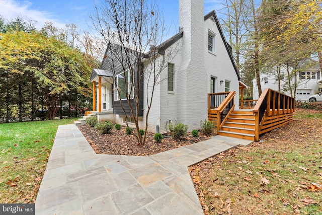 view of side of home with a wooden deck and a lawn