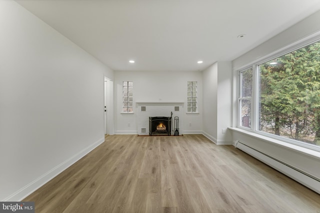 unfurnished living room with baseboard heating and light hardwood / wood-style floors