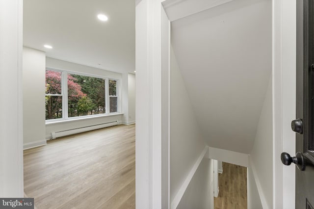 staircase featuring hardwood / wood-style floors, vaulted ceiling, and a baseboard heating unit