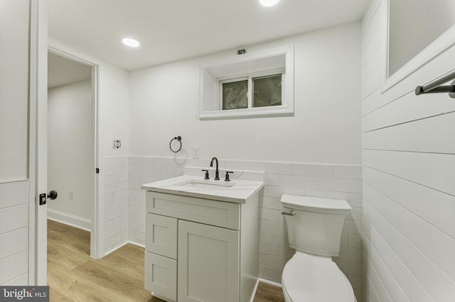 bathroom featuring hardwood / wood-style floors, vanity, toilet, and tile walls