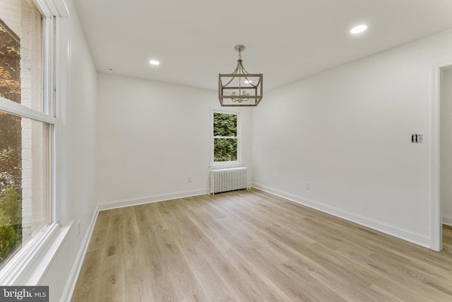 unfurnished dining area with an inviting chandelier, light hardwood / wood-style flooring, and radiator