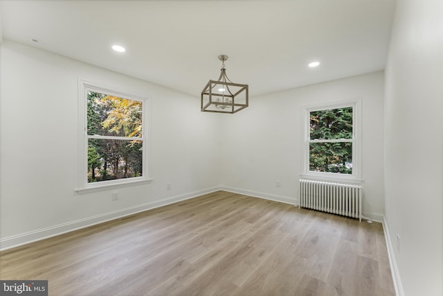 unfurnished room with a healthy amount of sunlight, light hardwood / wood-style floors, and radiator