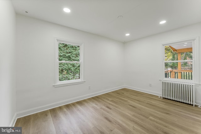 unfurnished room with radiator heating unit and light wood-type flooring