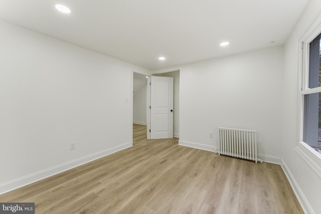 unfurnished room with light hardwood / wood-style floors and radiator heating unit