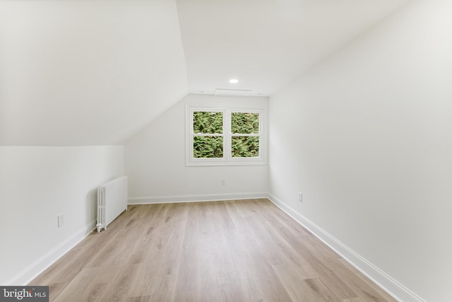 bonus room featuring radiator heating unit, vaulted ceiling, and light wood-type flooring