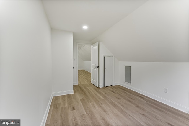 additional living space featuring vaulted ceiling and light wood-type flooring