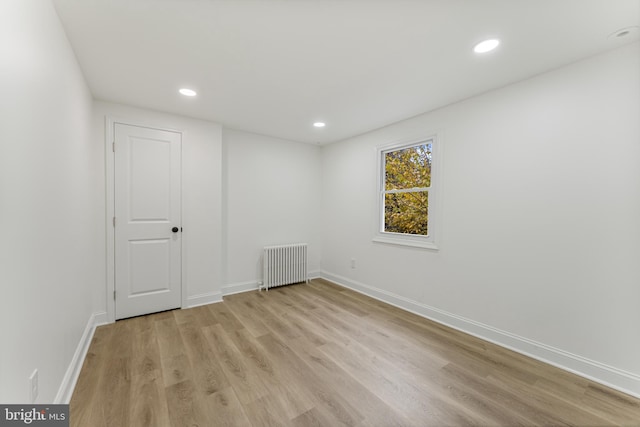 spare room featuring light wood-type flooring and radiator heating unit