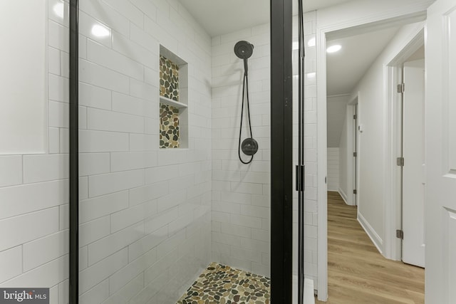 bathroom with wood-type flooring and tiled shower