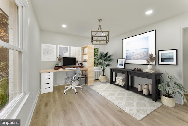 home office with radiator heating unit, light wood-type flooring, and an inviting chandelier