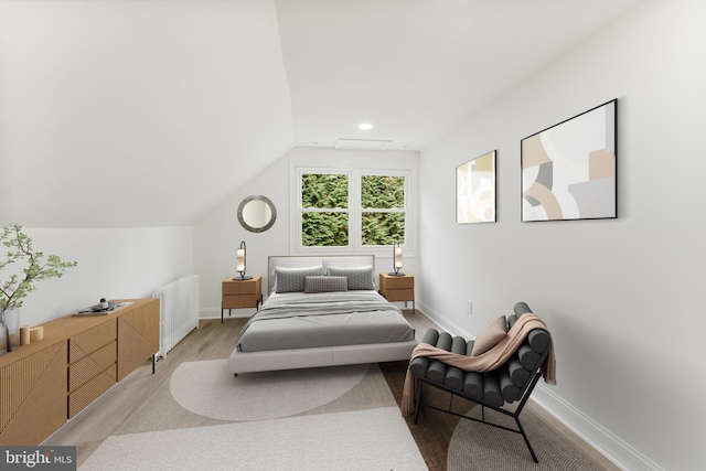 bedroom featuring lofted ceiling, radiator, and light hardwood / wood-style flooring