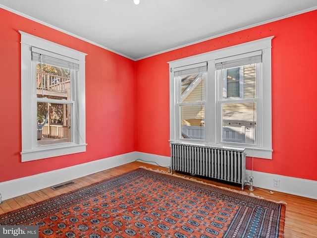 unfurnished room featuring radiator and hardwood / wood-style floors