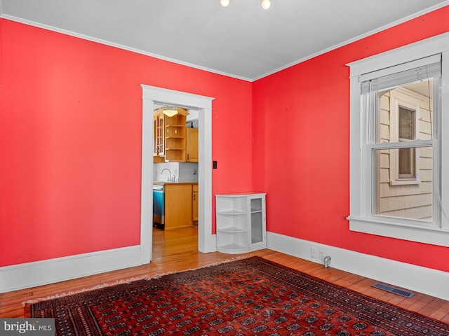 unfurnished room featuring hardwood / wood-style floors, ornamental molding, and sink