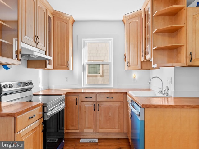 kitchen featuring appliances with stainless steel finishes, light brown cabinetry, sink, hardwood / wood-style flooring, and butcher block counters